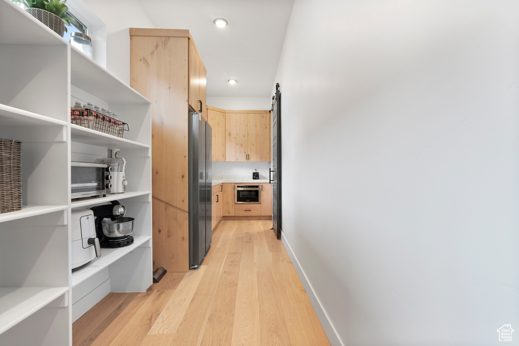 Hallway with a barn door and light hardwood / wood-style flooring