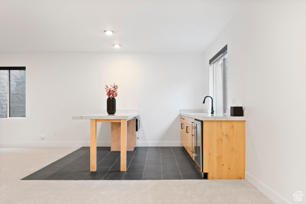 Interior space featuring dark carpet, light brown cabinetry, sink, and wine cooler