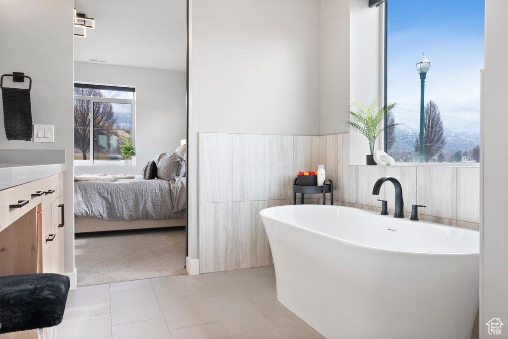 Bathroom featuring tile patterned flooring, vanity, and a tub to relax in