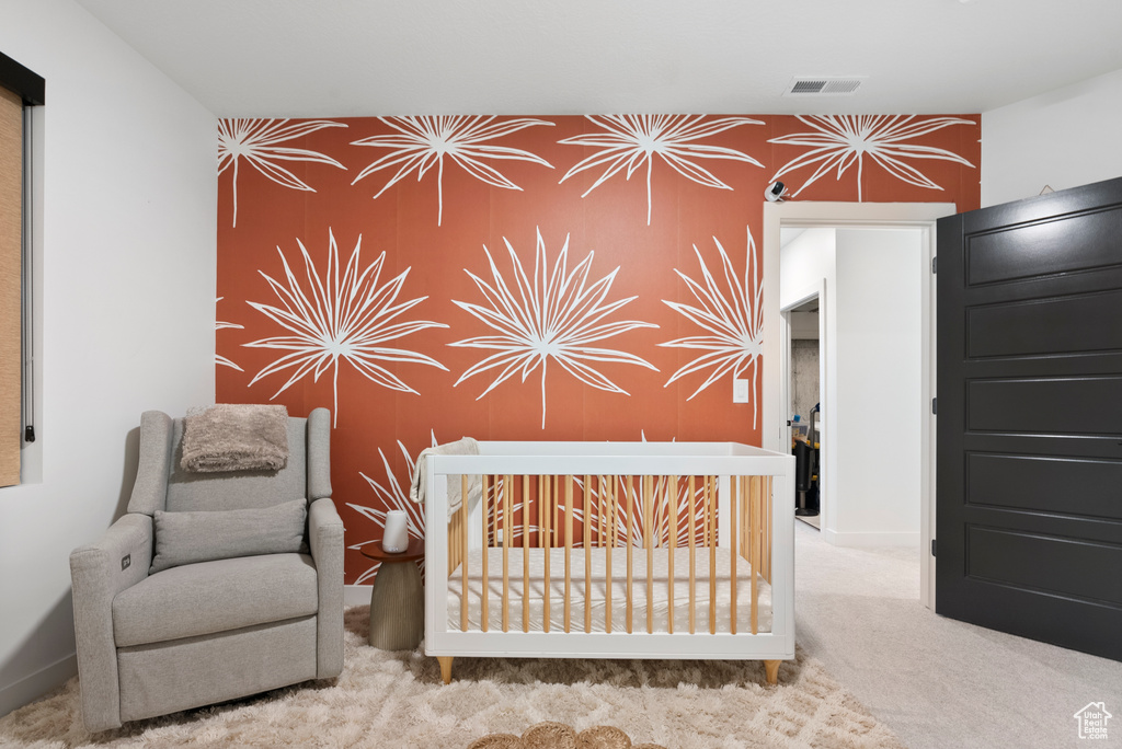 Unfurnished bedroom featuring light colored carpet and a nursery area