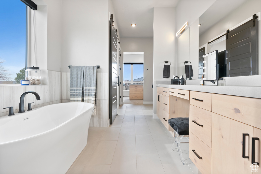 Bathroom featuring tile patterned floors, a washtub, and vanity