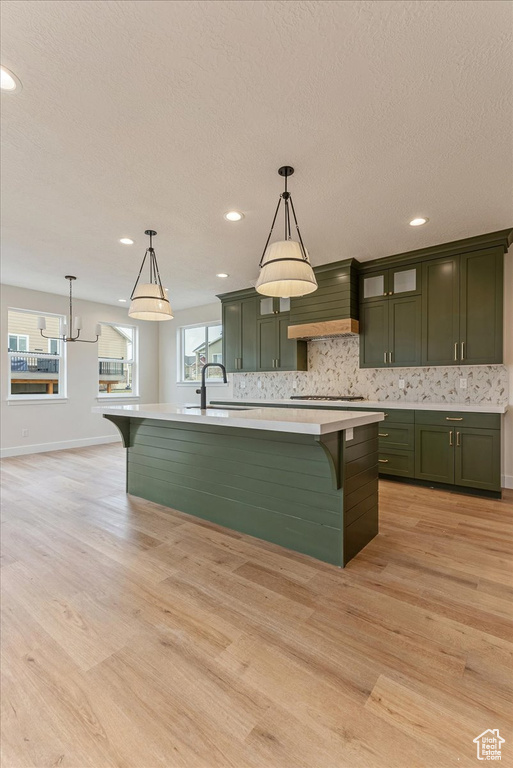 Kitchen with sink, light hardwood / wood-style flooring, hanging light fixtures, and green cabinetry
