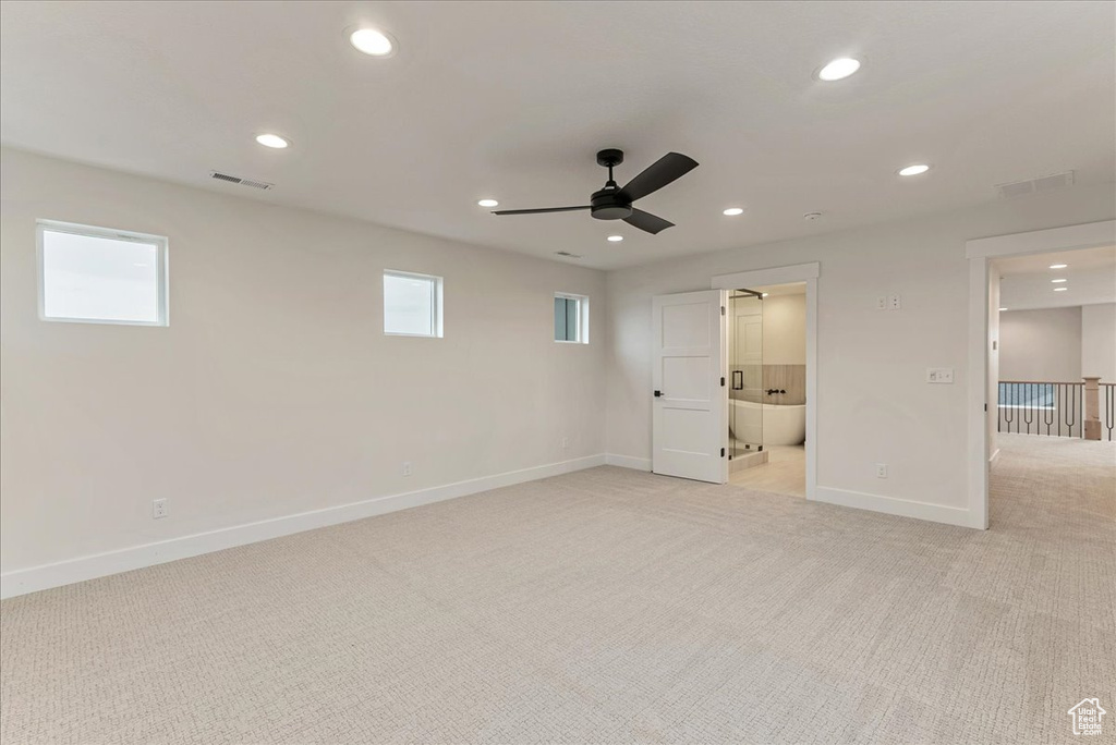 Unfurnished bedroom with ensuite bath, ceiling fan, light colored carpet, and multiple windows