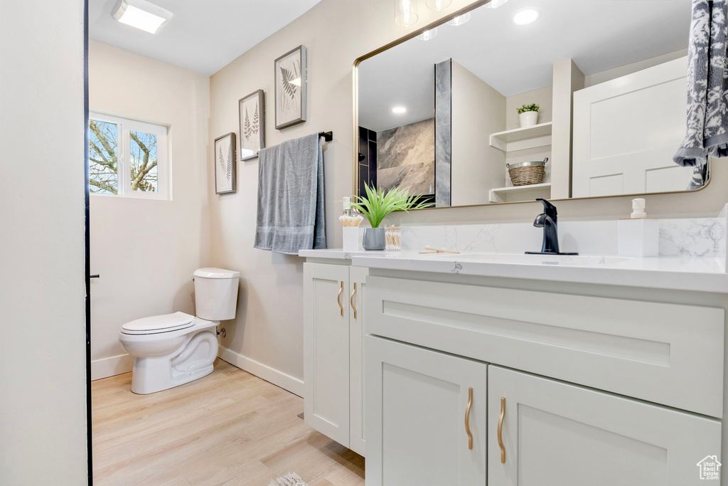 Full bath with toilet, recessed lighting, wood finished floors, vanity, and baseboards