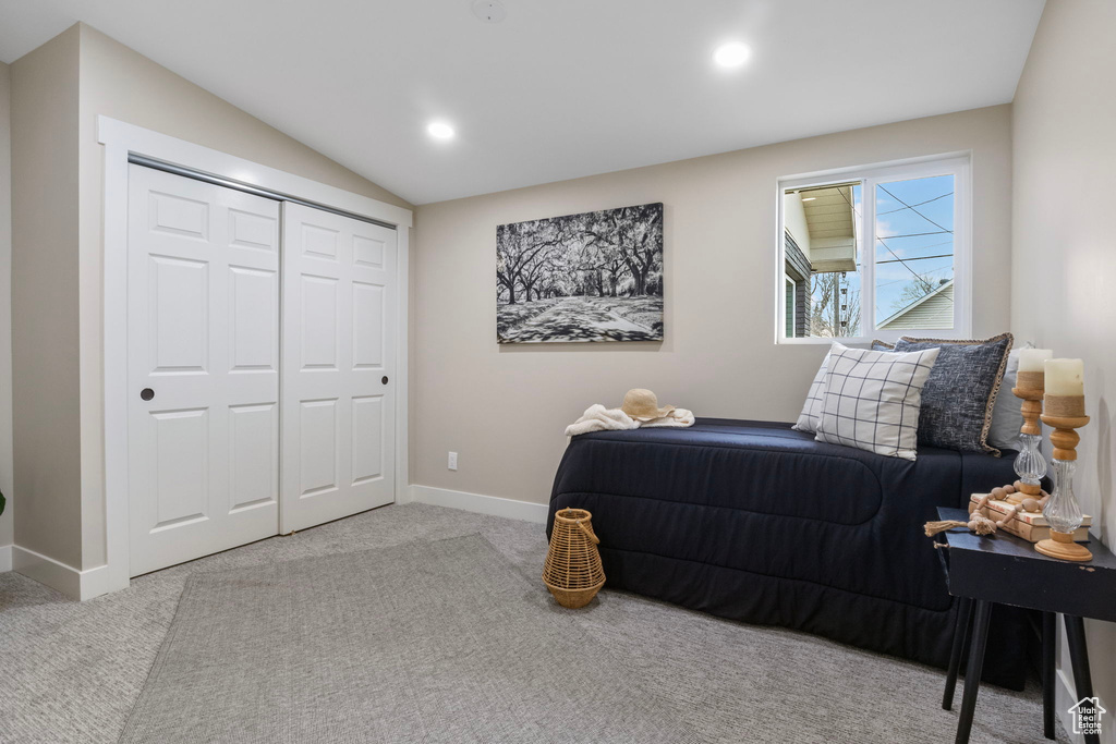 Carpeted bedroom with a closet and lofted ceiling