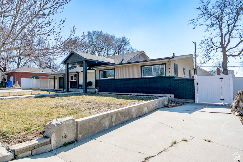 View of front of home with a gate, fence, a front lawn, and brick siding