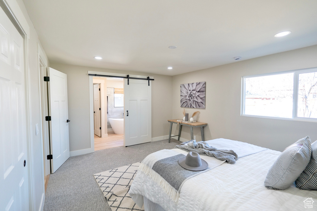 Bedroom featuring recessed lighting, a barn door, light carpet, ensuite bath, and baseboards