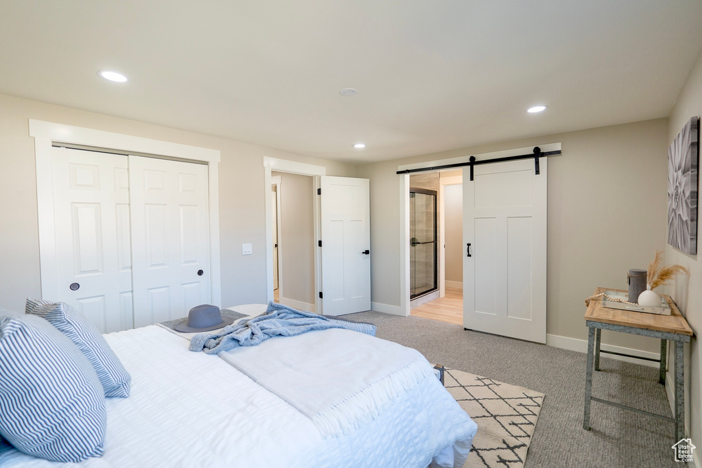 Bedroom featuring light carpet, a barn door, a closet, and recessed lighting