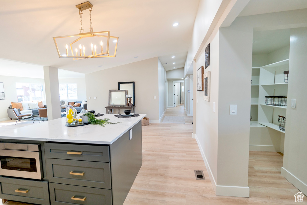 Kitchen with visible vents, open floor plan, hanging light fixtures, light wood-type flooring, and gray cabinets