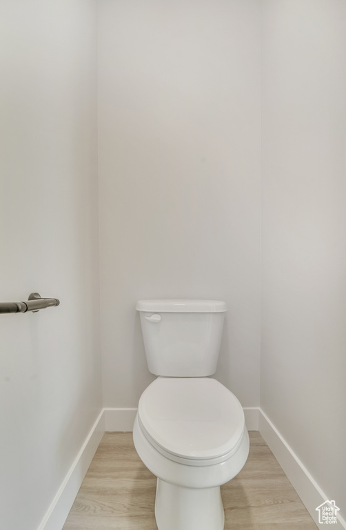 Bathroom featuring baseboards, wood finished floors, and toilet