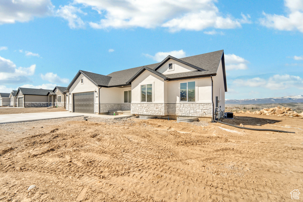 Modern farmhouse featuring stone siding, stucco siding, driveway, and a garage