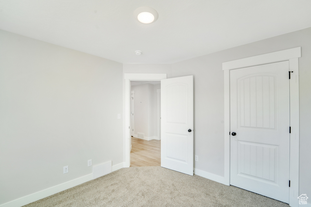 Unfurnished bedroom with baseboards, visible vents, and light carpet
