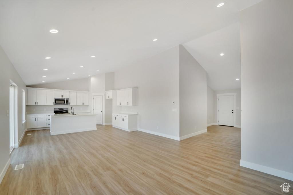 Unfurnished living room with a sink, light wood-type flooring, baseboards, visible vents, and recessed lighting
