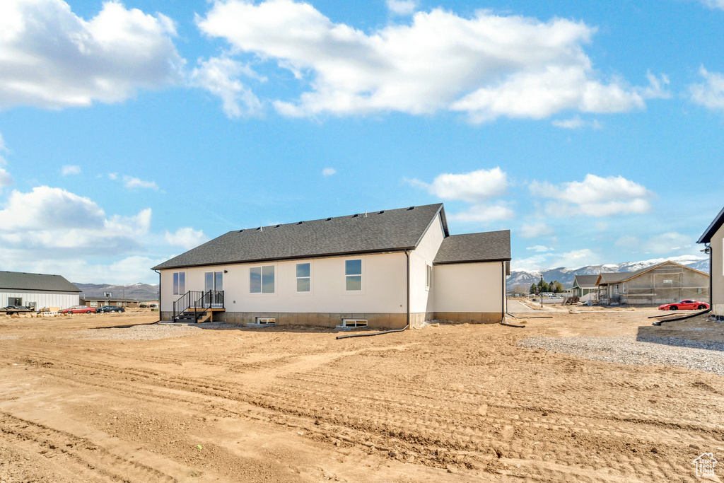 Back of property featuring a mountain view and roof with shingles