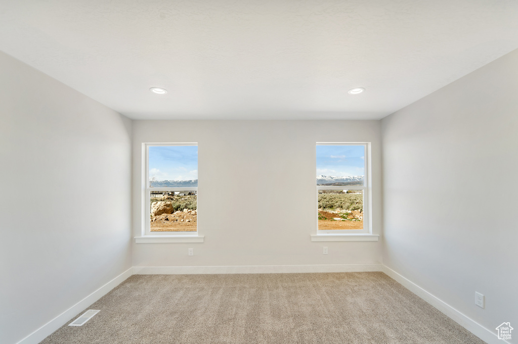 Spare room with baseboards, visible vents, recessed lighting, and light carpet