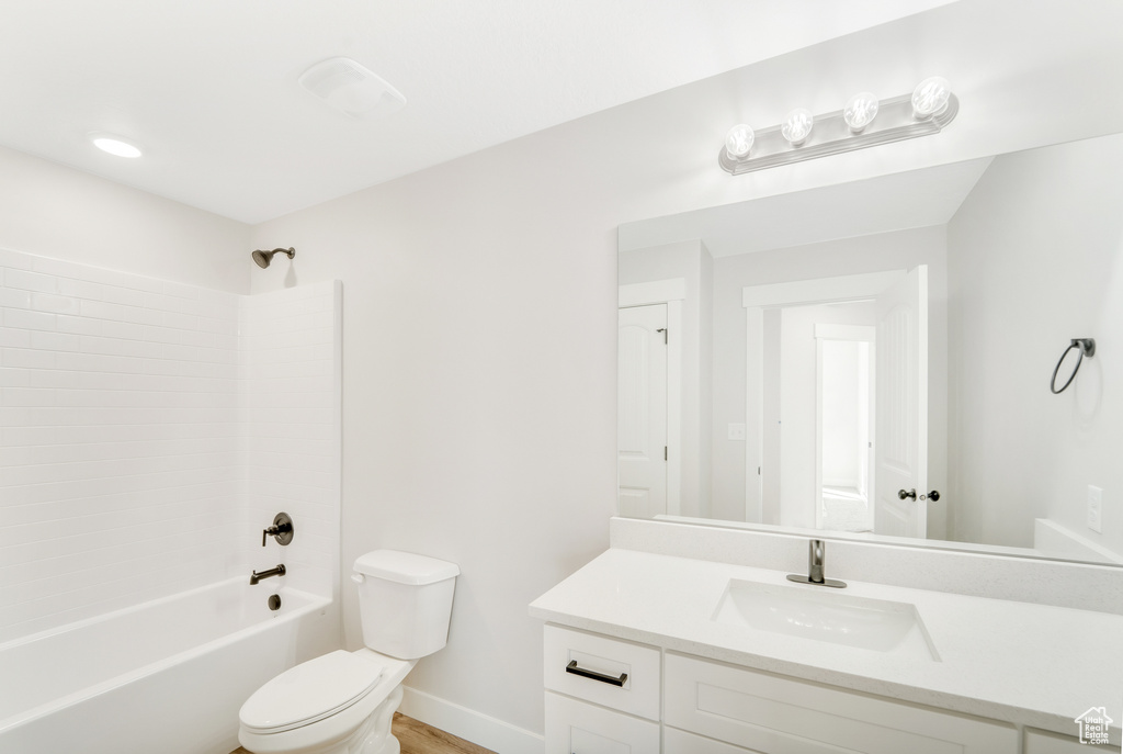 Bathroom featuring toilet, vanity, baseboards, and bathing tub / shower combination