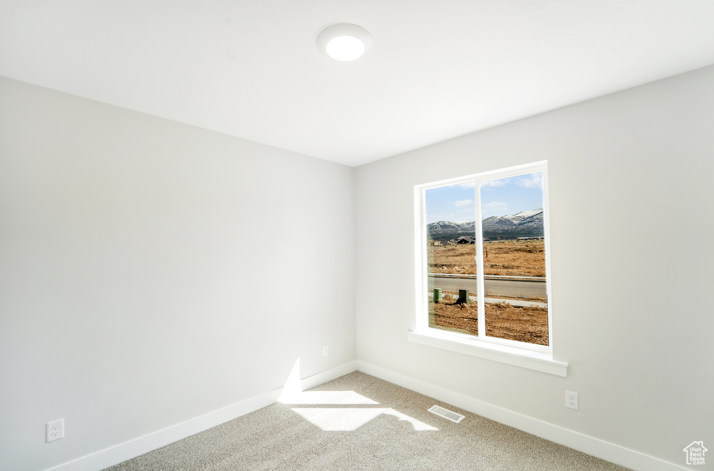 Spare room featuring baseboards, visible vents, and light colored carpet