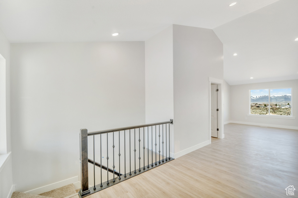 Interior space featuring baseboards, an upstairs landing, wood finished floors, and recessed lighting