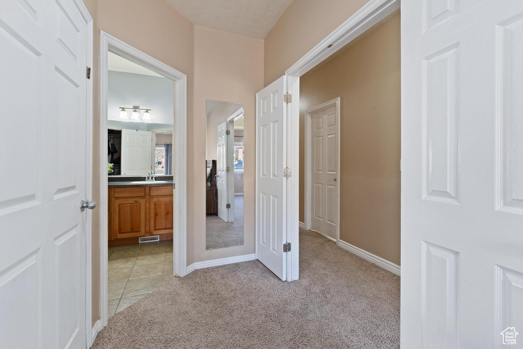 Hall featuring sink and light colored carpet
