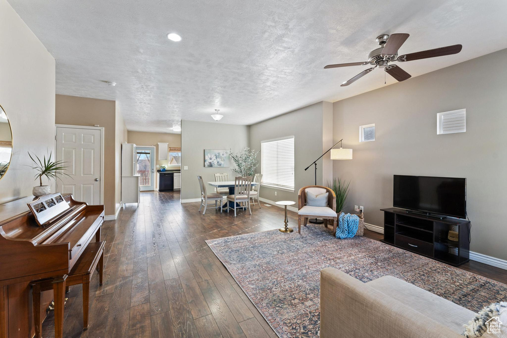 Living room featuring a textured ceiling, ceiling fan, a healthy amount of sunlight, and dark hardwood / wood-style floors