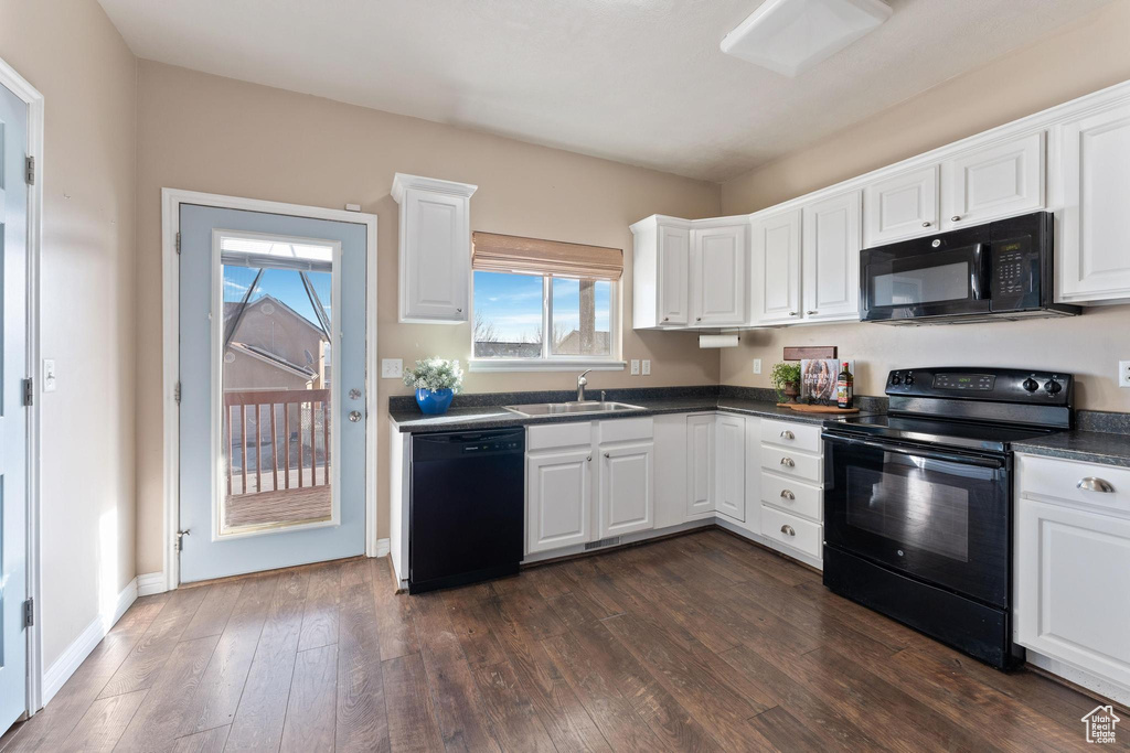 Kitchen with sink, dark hardwood / wood-style floors, white cabinetry, and black appliances