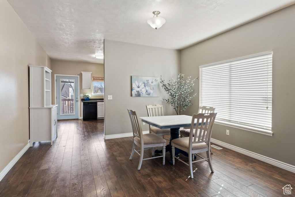 Dining room with a textured ceiling and dark hardwood / wood-style floors