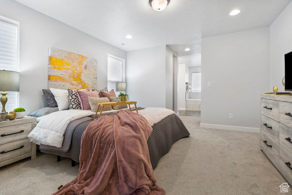 Bedroom with ensuite bath and light colored carpet