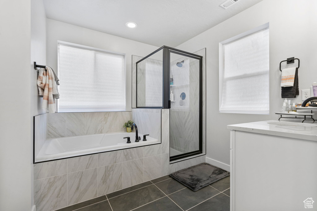 Bathroom with tile patterned flooring, vanity, and shower with separate bathtub