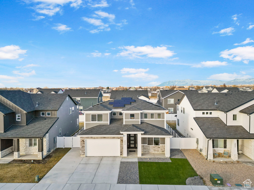 View of front facade with a mountain view, solar panels, and a front lawn