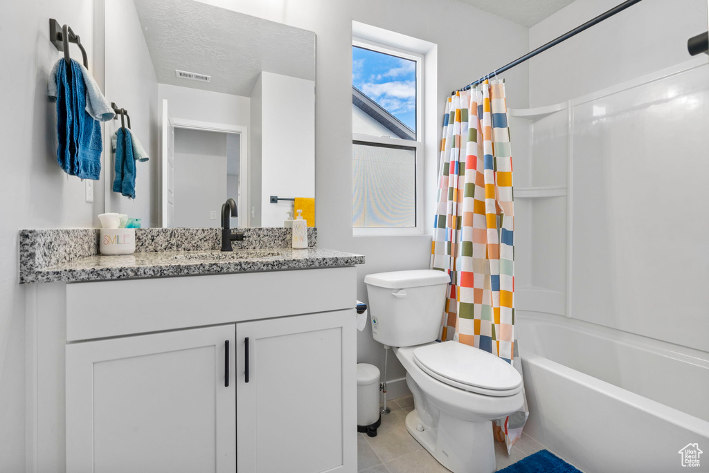 Full bathroom with a textured ceiling, vanity, shower / tub combo, and toilet