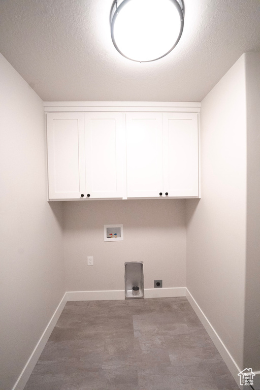Washroom featuring baseboards, a textured ceiling, hookup for a washing machine, cabinet space, and wood finished floors