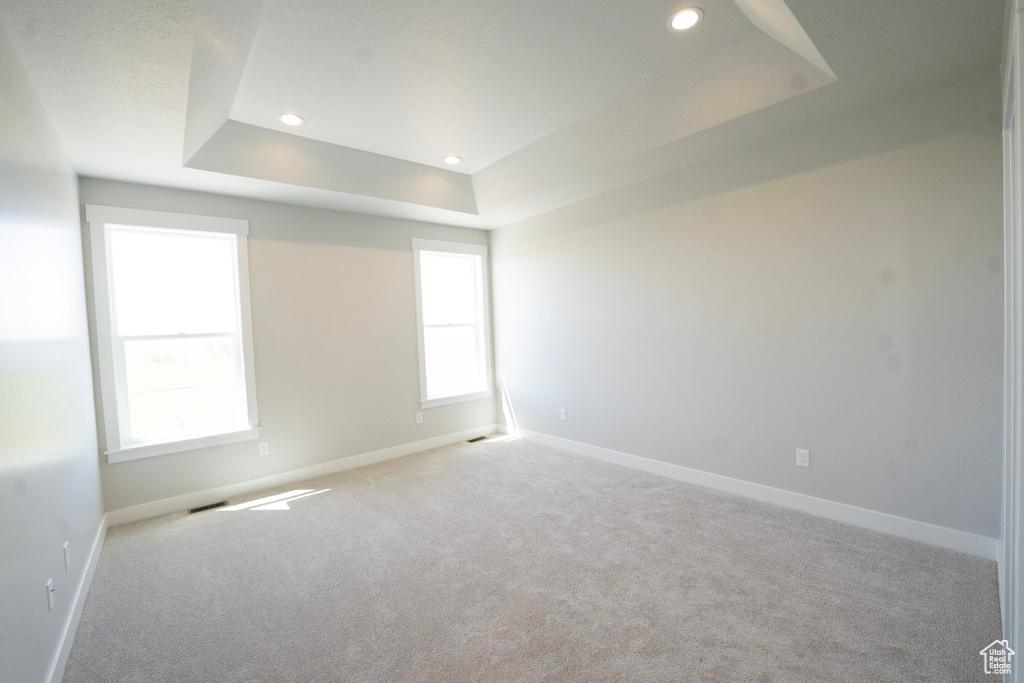 Empty room with a raised ceiling, carpet flooring, baseboards, healthy amount of natural light, and recessed lighting