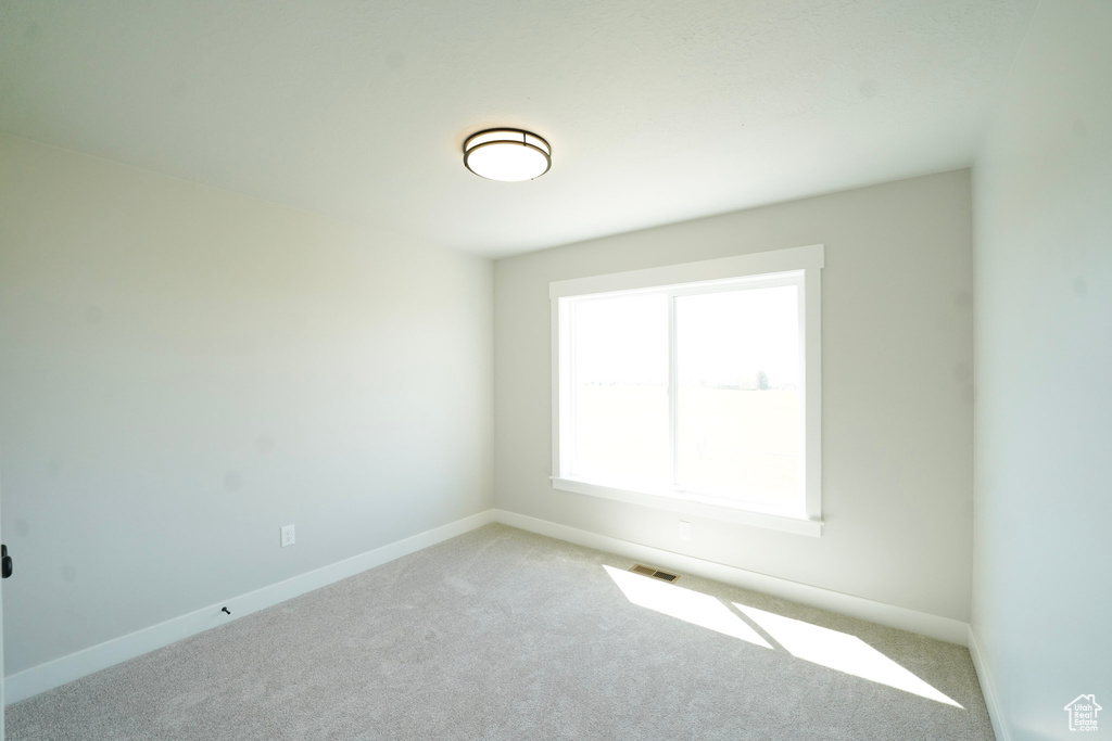 Carpeted spare room featuring baseboards