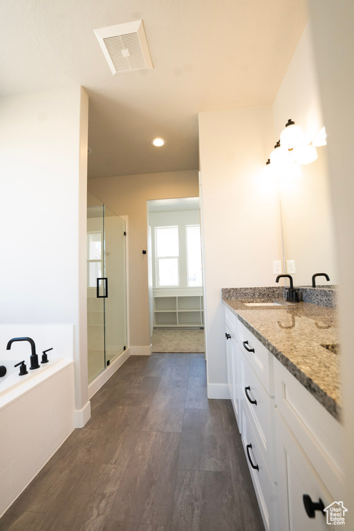 Full bathroom featuring a stall shower, a bath, wood finished floors, vanity, and recessed lighting