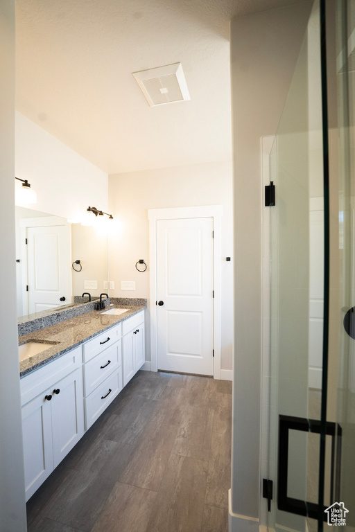 Full bath featuring double vanity, wood finished floors, and a shower with shower door