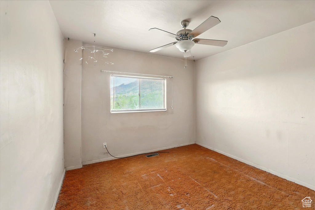 Carpeted spare room featuring baseboards and a ceiling fan