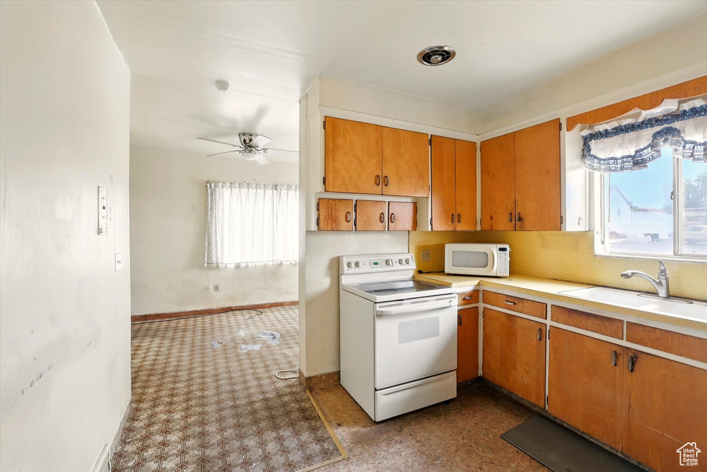 Kitchen featuring white appliances, light countertops, a sink, and brown cabinets