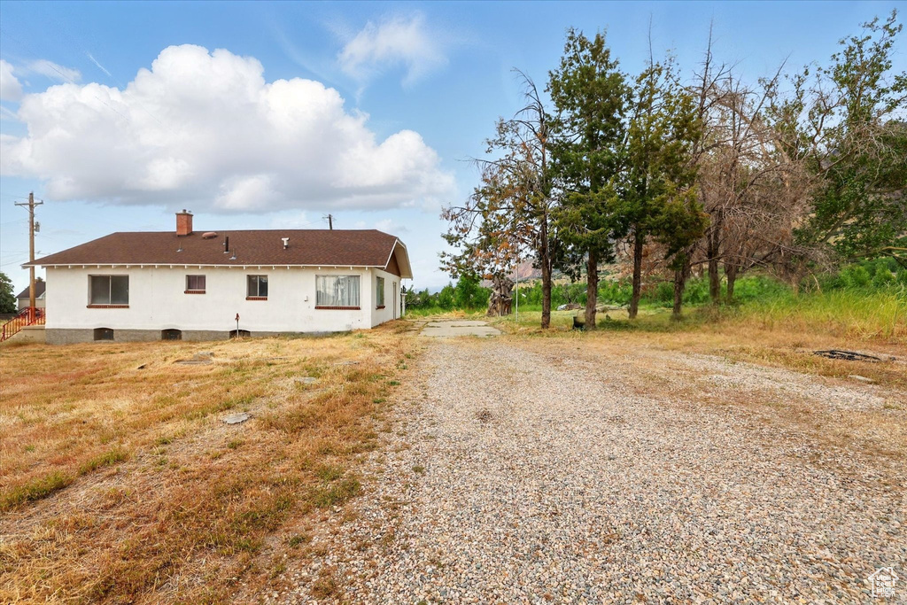 View of side of property with gravel driveway and a chimney