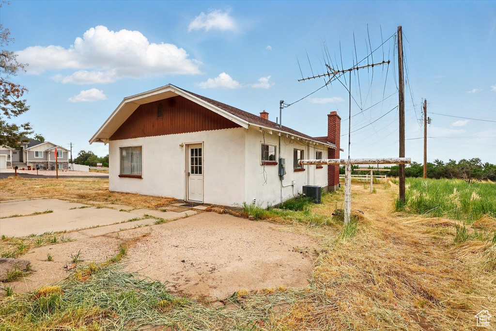 View of side of property featuring a chimney and stucco siding