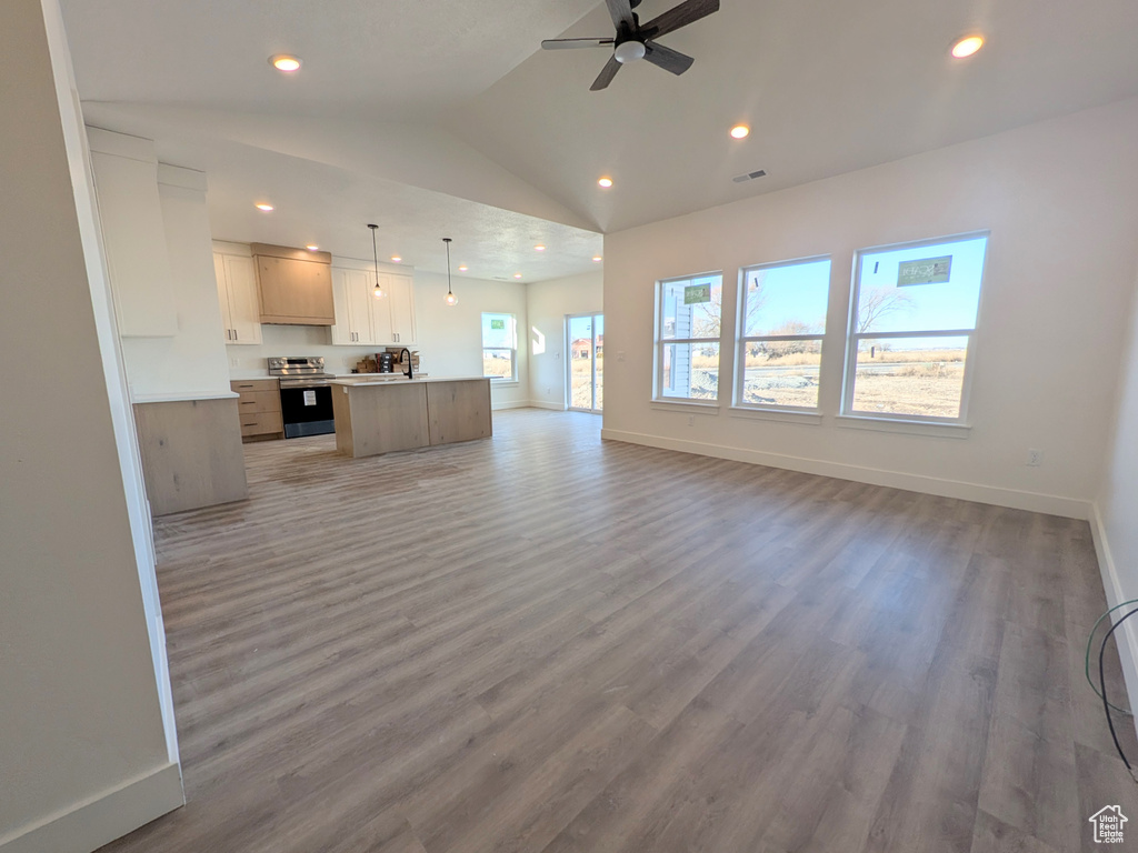 Unfurnished living room featuring ceiling fan, hardwood / wood-style floors, and vaulted ceiling
