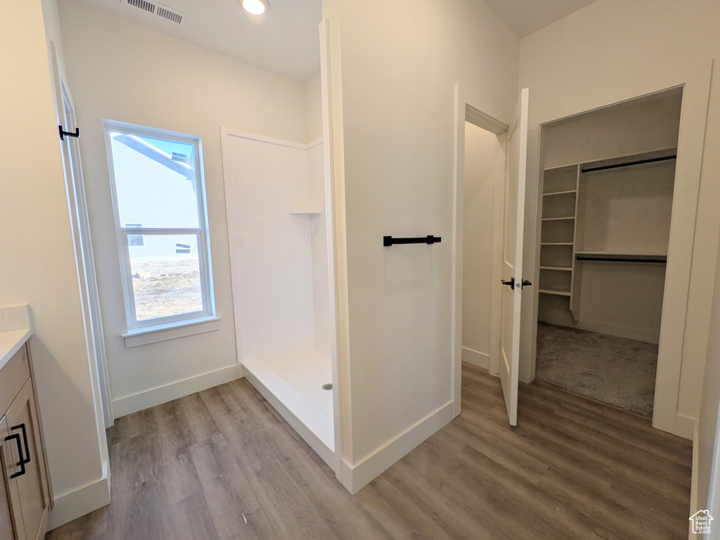 Bathroom featuring vanity, wood-type flooring, and walk in shower