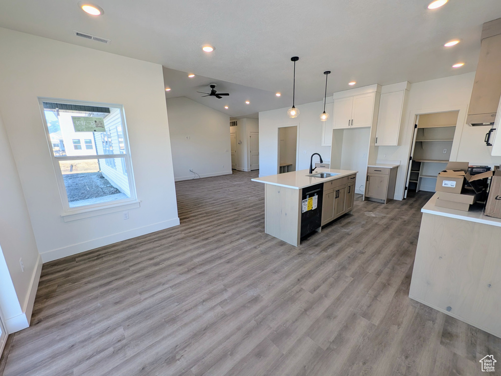 Kitchen featuring ceiling fan, sink, dishwasher, pendant lighting, and a kitchen island with sink