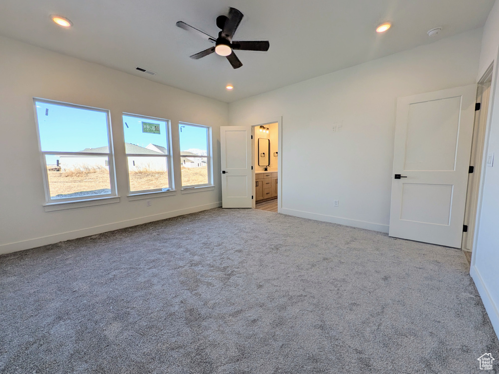 Unfurnished bedroom with ceiling fan, light colored carpet, and ensuite bathroom