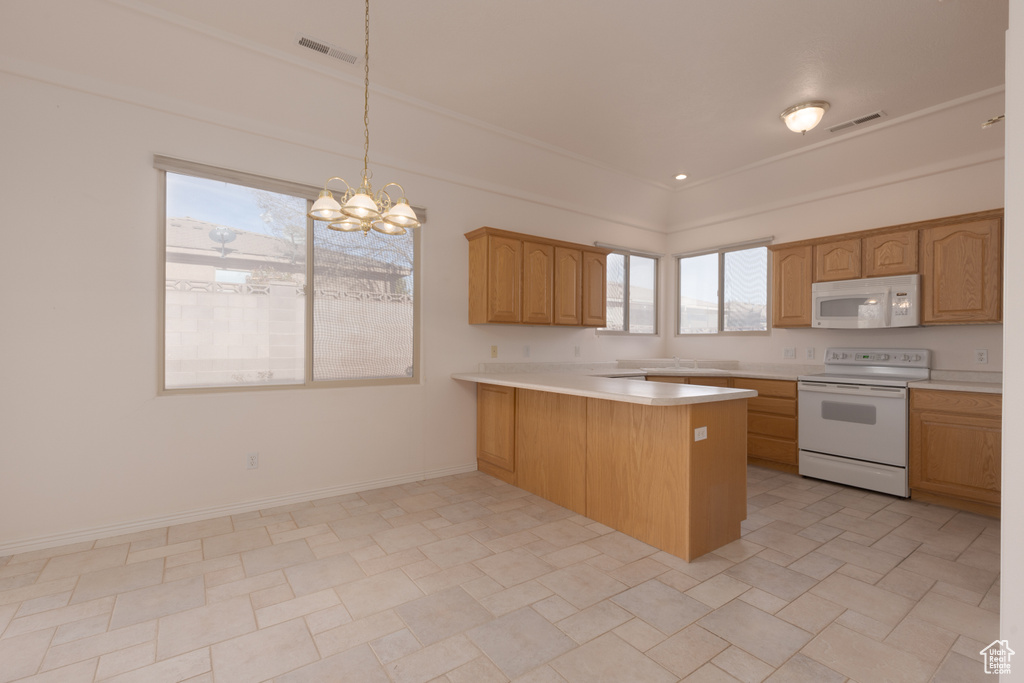 Kitchen with an inviting chandelier, kitchen peninsula, crown molding, decorative light fixtures, and white appliances