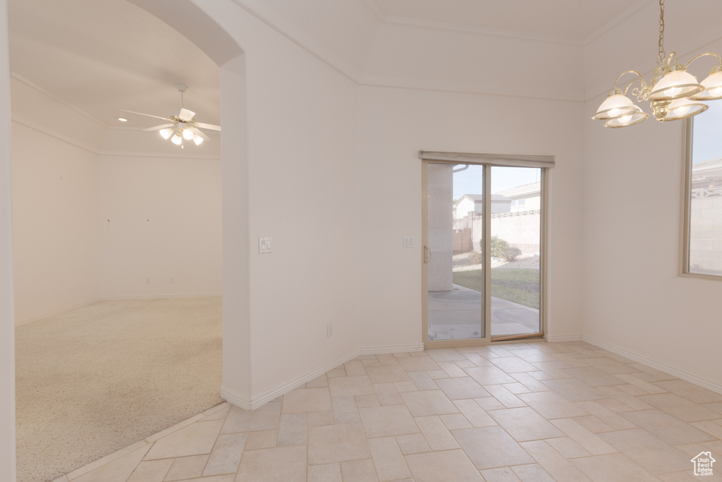 Empty room featuring ceiling fan with notable chandelier, light colored carpet, and ornamental molding