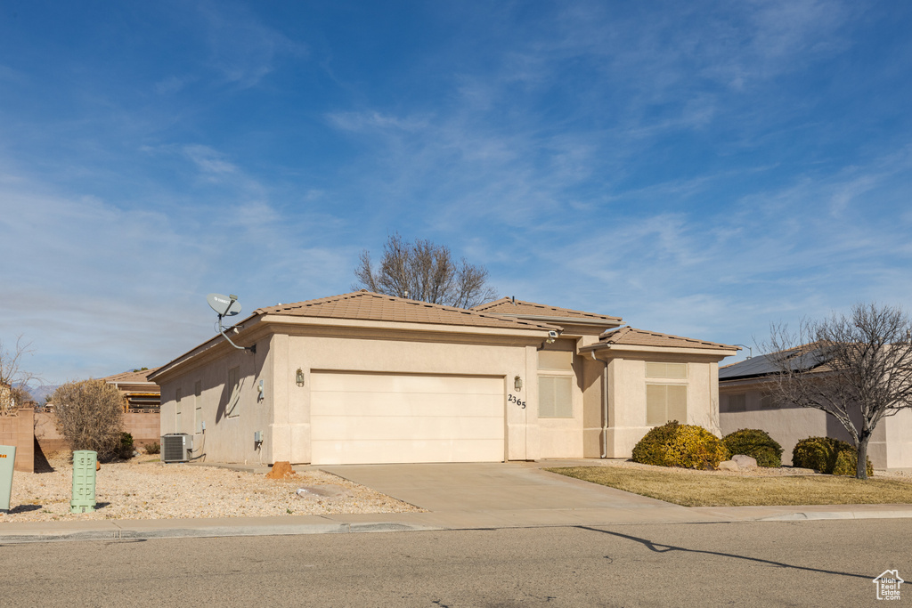 View of front of house with central air condition unit and a garage