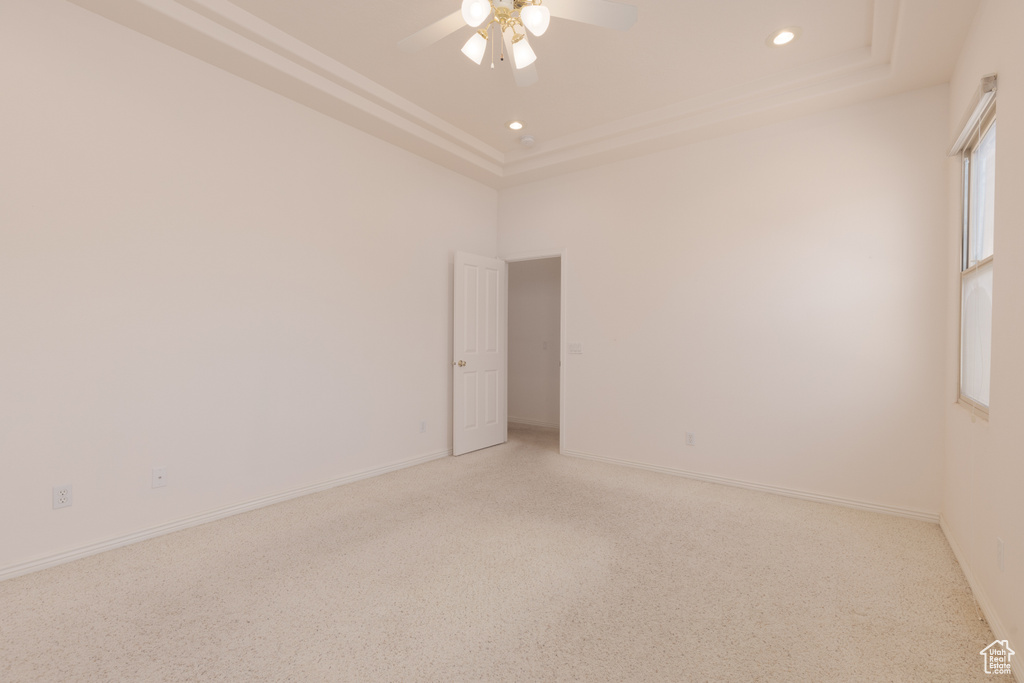 Carpeted spare room with ceiling fan and a tray ceiling