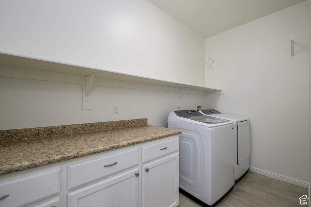 Laundry room with light hardwood / wood-style flooring and washing machine and clothes dryer