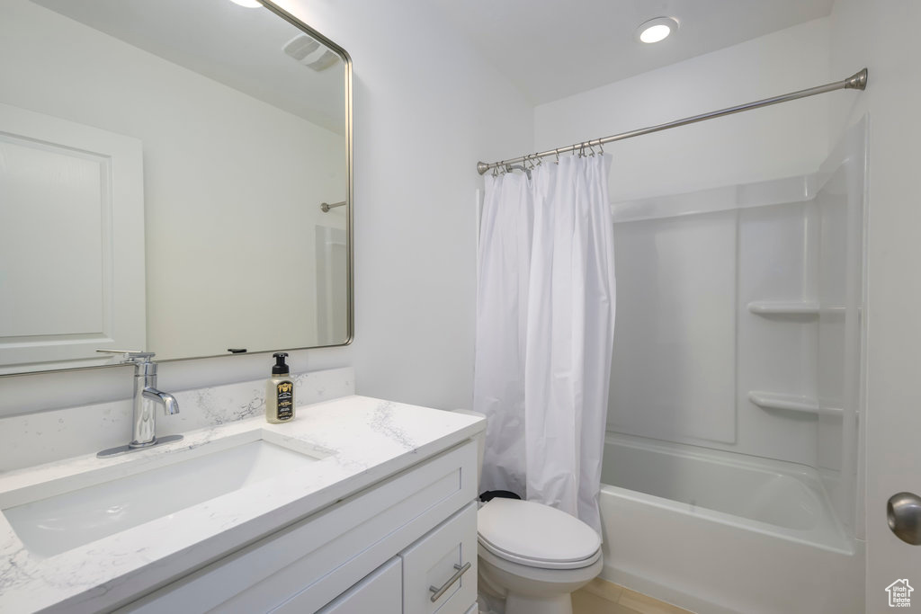 Full bathroom with vanity, shower / tub combo, and toilet