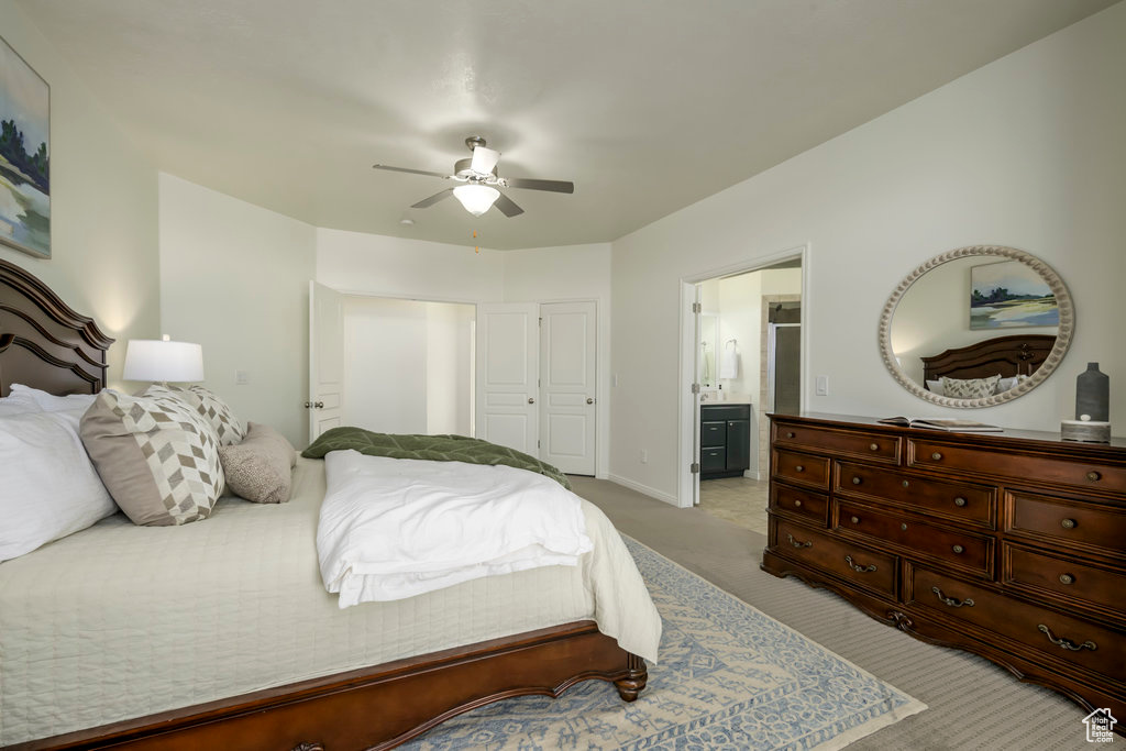Carpeted bedroom featuring a closet, ensuite bath, and ceiling fan